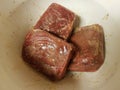 Frozen seasoned beef meat squares in white plastic container