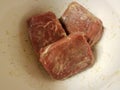 Frozen seasoned beef meat squares in white plastic container