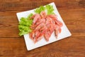 Frozen shrimps with lettuce on square dish on wooden surface