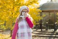 Frozen sick girl with a handkerchief, background yellow autumn trees