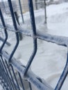Frozen snow on a blue iron fence
