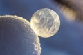 Frozen soap bubble ball on snow in sunset, crystal formation