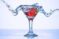Frozen splashes of clean, spring water, in a glass with frozen strawberries, white background Royalty Free Stock Photo