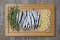 Frozen sprats on a kitchen board with lemons and rosemary Royalty Free Stock Photo