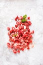 Frozen strawberries with ice cubes scattered on table