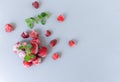 Frozen strawberries with sprigs of lemon balm on a gray background.
