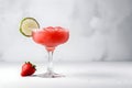 Frozen strawberry margarita garnished with a salt rim and a lime slice on grey, copy space. Margarita with crushed ice. Frozen red Royalty Free Stock Photo