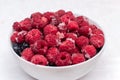 Frozen Summer Berries in a Bowl - Tasty Raspberries and blueberries. Bowl with frozen ripe berries on a white table Royalty Free Stock Photo