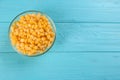 Frozen sweet corn on light blue table, top view with space for text. Vegetable preservation