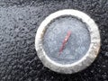 A frozen thermometer cover with wet snow on a bbq grill