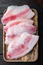 Frozen tilapia fish meat, on old wooden table, top view