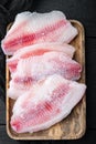 Frozen tilapia fish meat, on old wooden table, top view