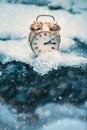 Frozen time. A clock on an ice next to the water. Extreme weather situation. Snow falling on a clock in a nature.