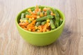 Frozen vegetable mix in green glass bowl on table