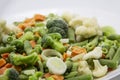 Frozen vegetables: cauliflower, green peas, leeks, broccoli, carrots, green beans on a white plate