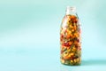 Frozen vegetables in a transparent glass bottle on a light blue background. Royalty Free Stock Photo