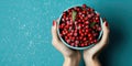 Frozen viburnum berries in a bowl in hands on a blue background