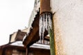 Frozen water flowing from the roof through a damaged, rusty, metal gutter that is on the facade of the building. Royalty Free Stock Photo