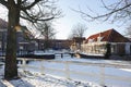 Frozen water and show on canal and traditional old brick buildings with tile roofs at sunny winter day in Hoorn city, Holland