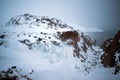 Frozen waterfall on the background of hills on the Kola Peninsula and a man standing on the edge of the cliff and looking into the