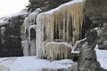 Frozen waterfall in gray rocks. Icicles and snow in winter cold temperature.