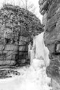 Frozen waterfall spilling out between two high natural layered r