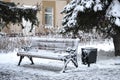 Frozen winter city landscape with snow-covered bench Royalty Free Stock Photo