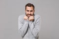 Frozen young bearded man in gray sweater posing isolated on grey background studio portrait. Healthy fashion lifestyle