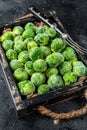 Frozen young Brussels sprouts green cabbage in wooden tray. Black background. Top view