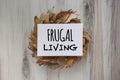 Frugal Living sign laying on circle of dried brown leafs