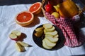 Fruit basket, cut into halves orange grapefruit apple in basket on a red napkin, pear slices on a black plate Royalty Free Stock Photo