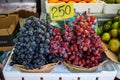 Fruit baskets of fresh sweet black and red grapes selling in local market with price tag