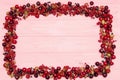 Fruit berries frame - redcurrants, gooseberries and blueberries on pink wooden background