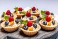 Fruit and berry tartlets dessert assorted on wooden tray. Closeup of delicious pastry sweets pies colorful cakes with fresh Royalty Free Stock Photo