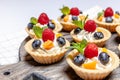 Fruit and berry tartlets dessert assorted on wooden tray. Closeup of delicious pastry sweets pies colorful cakes with fresh Royalty Free Stock Photo