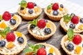 Fruit and berry tartlets dessert assorted on wooden tray. Closeup of delicious pastry sweets pies colorful cakes with fresh Royalty Free Stock Photo
