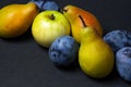 Fruit on a black background. Plums, pears and apples lie side by side. Royalty Free Stock Photo