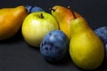 Fruit on a black background. Plums, pears and apples lie side by side. Royalty Free Stock Photo
