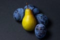 Fruit on a black background. Plums and pears are in a heap