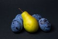Fruit on a black background. Plums and pears are in a heap