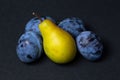 Fruit on a black background. Plums and pears are in a heap