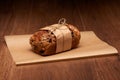 Fruit bread with raisins, prunes and nuts in baking paper on dark wooden table