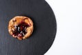 Fruit bun with honey on round black rock stand on white background. Puff with fruit and honey in cafe. View from above