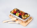 Fruit cake in aluminum foil loaf pan on wooden plate with wooden Royalty Free Stock Photo