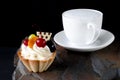 Fruit cake with cherries, grapes and plum stands on a wild stone next to a white cup of coffee with a foam Royalty Free Stock Photo