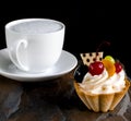 Fruit cake with cherries, grapes and plum stands on a wild stone next to a white cup of coffee with a foam Royalty Free Stock Photo