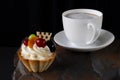 Fruit cake with cherries, grapes and plum stands on a wild stone next to a white cup of coffee with a foam Royalty Free Stock Photo