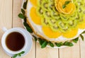 Fruit cake (orange, kiwi, mint) with a white cup of te Royalty Free Stock Photo