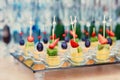Fruit canapes on a glass tray, on the background of wine glasses and champagne. Catering concept