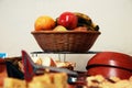 A fruit casket with apple, banana and orange standing on a metal table with loads of other kitchen gear in front of it